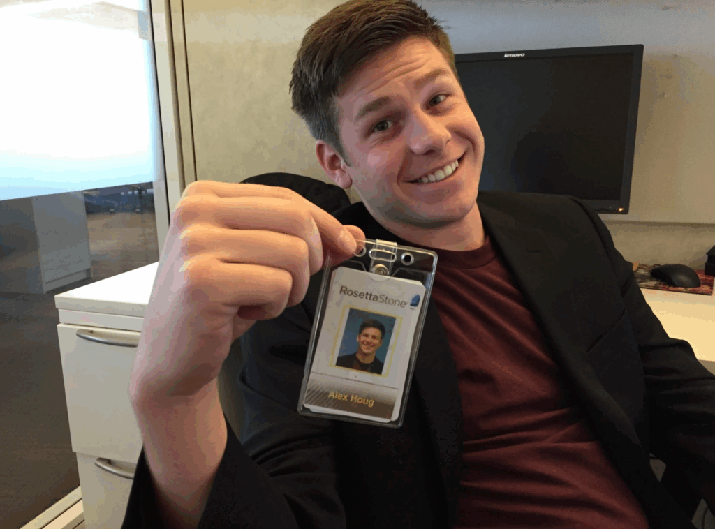 A team member smiles while displaying a visitor badge