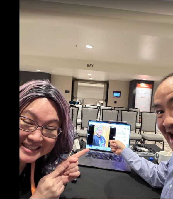 Liana Ling and Dennis Yu at DigiMarCon Toronto reviewing podcast content on a laptop