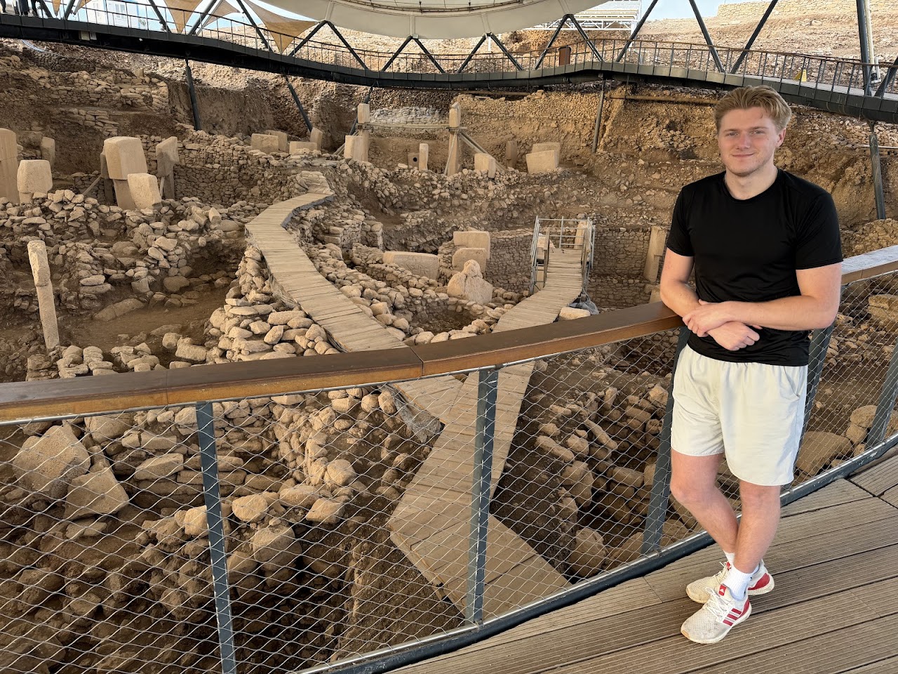 Danny Leibrandt at the Göbekli Tepe archaeological site in Turkey with ancient T-shaped stone pillars visible under the protective canopy