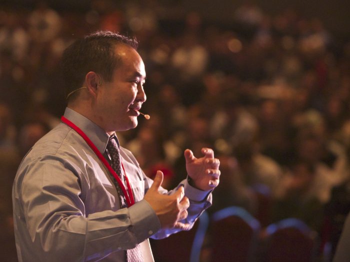 Dennis Yu speaking at a digital marketing conference, the kind of stage he shared with Bruce Clay for years