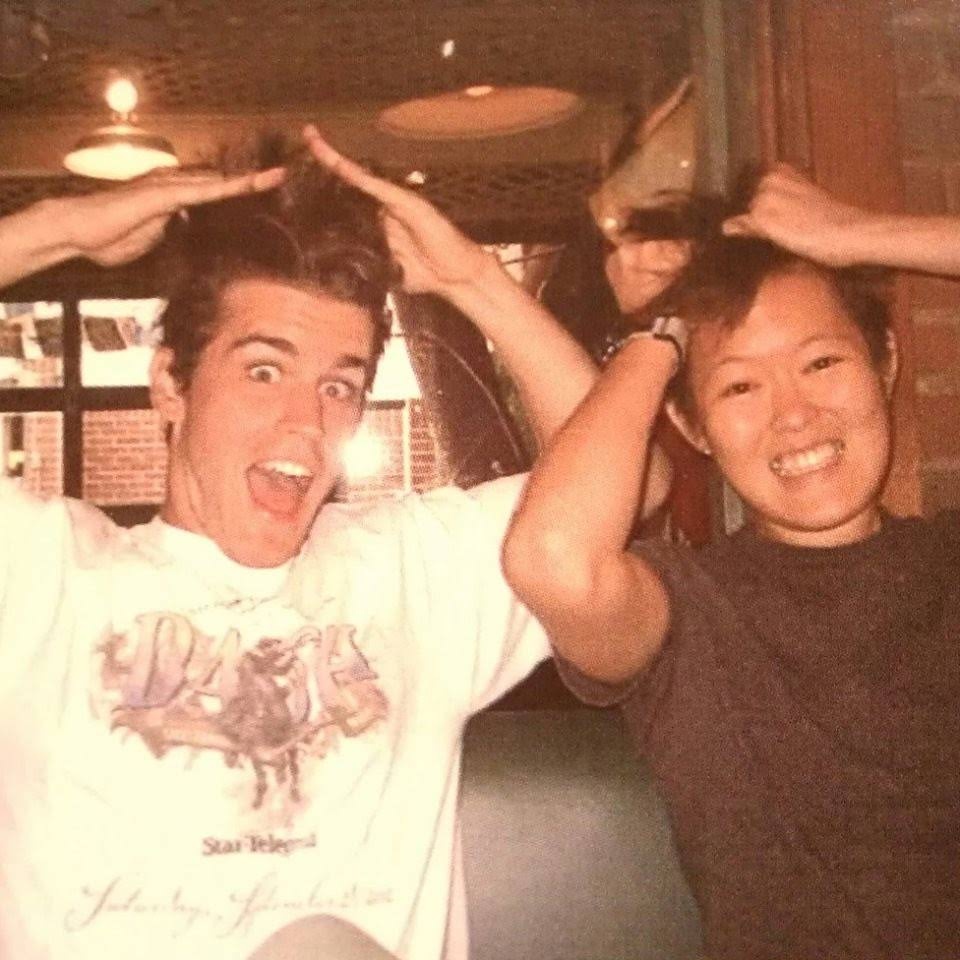 Chris Rummel and Dennis Yu in a booth, hands up as antlers, Chris in a Dallas Star-Telegram shirt