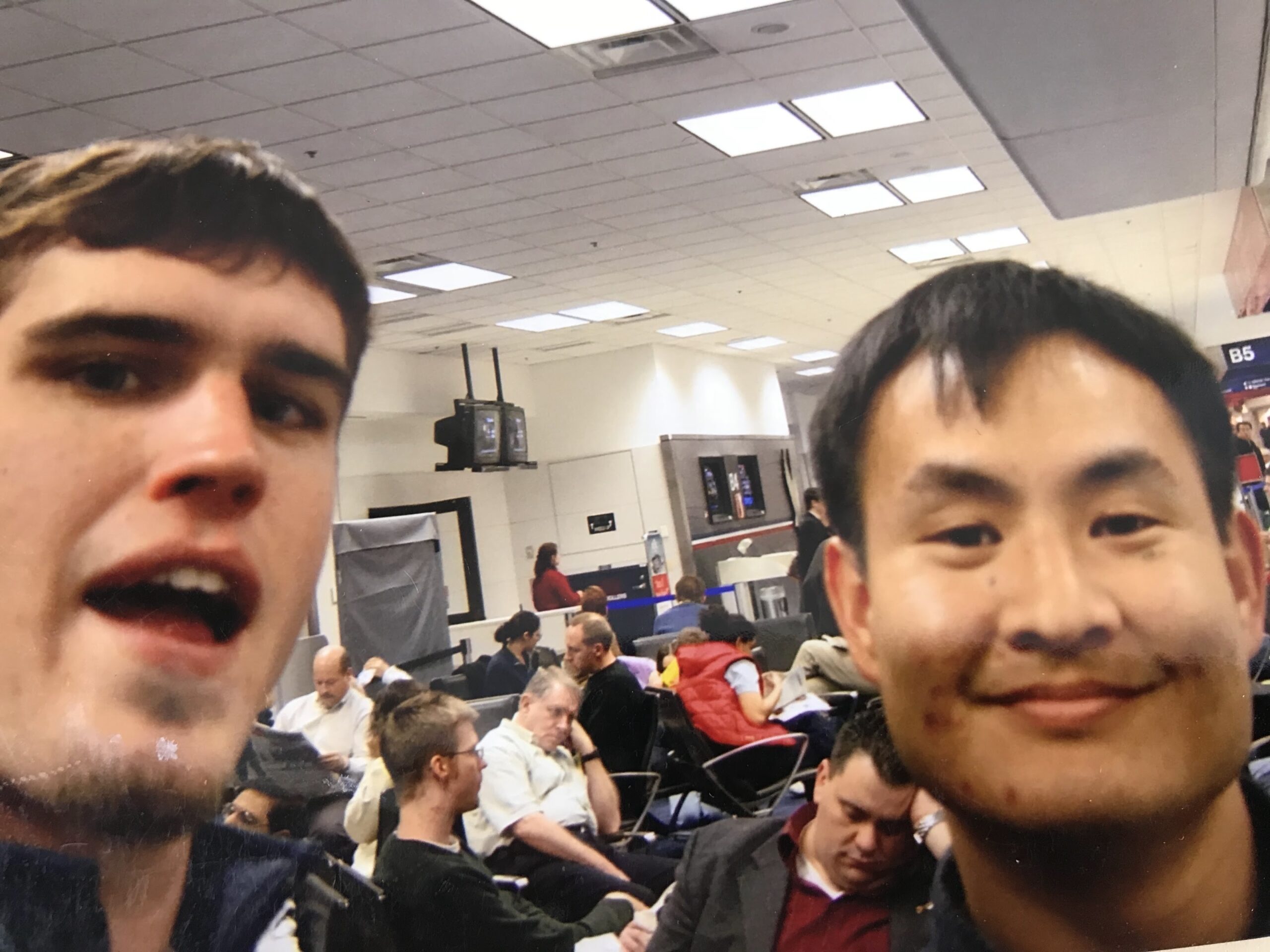 Dennis Yu and Chris Rummel in a close airport selfie, gate chairs behind them