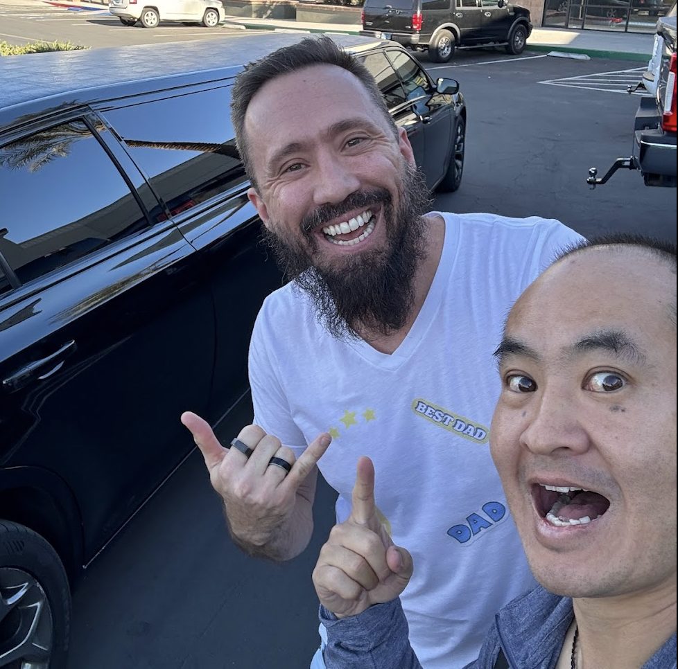 Dennis Yu and Damon Burton smiling in a parking lot in front of the black limo