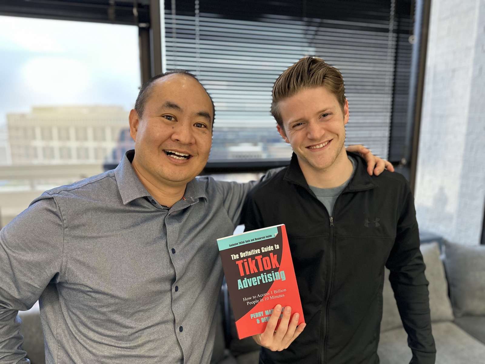 Dennis Yu with a colleague holding the TikTok advertising paperback in an office