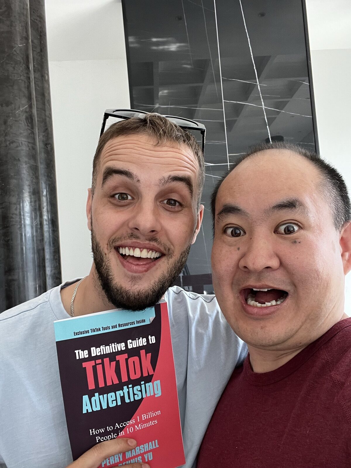 Two men indoors holding The Definitive Guide to TikTok Advertising