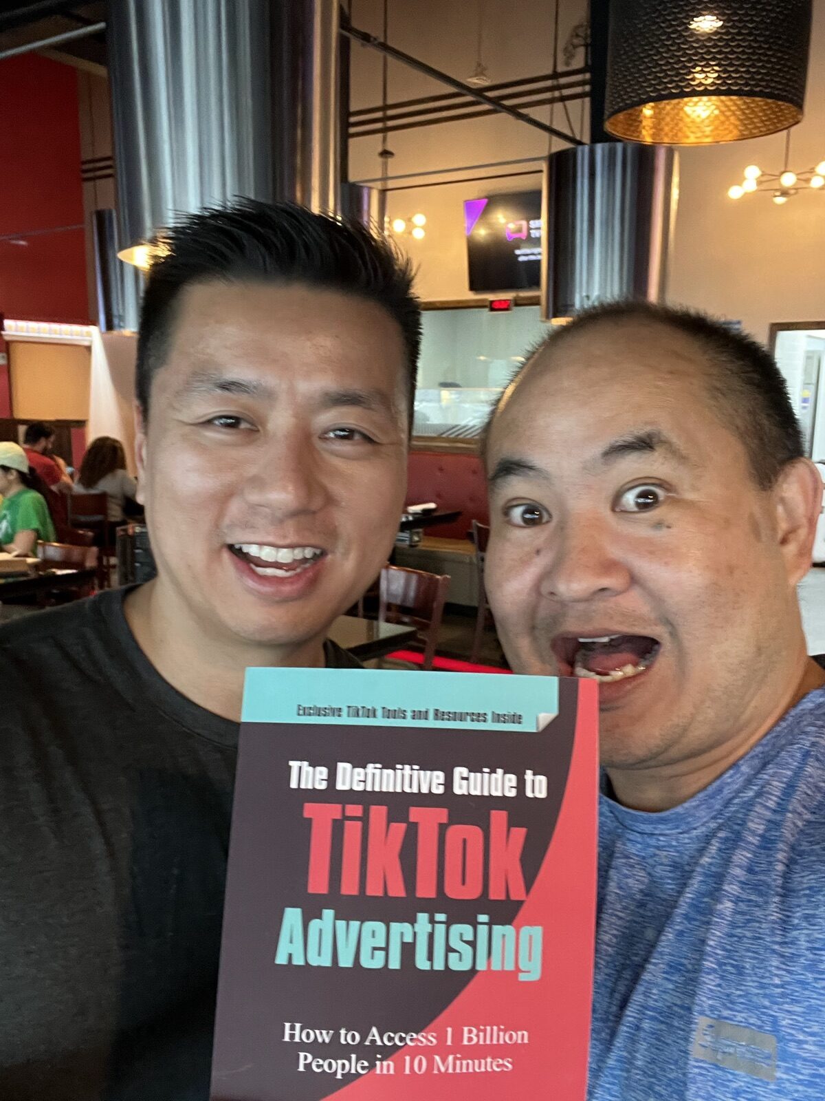 Two men in a conference lounge holding the TikTok advertising paperback