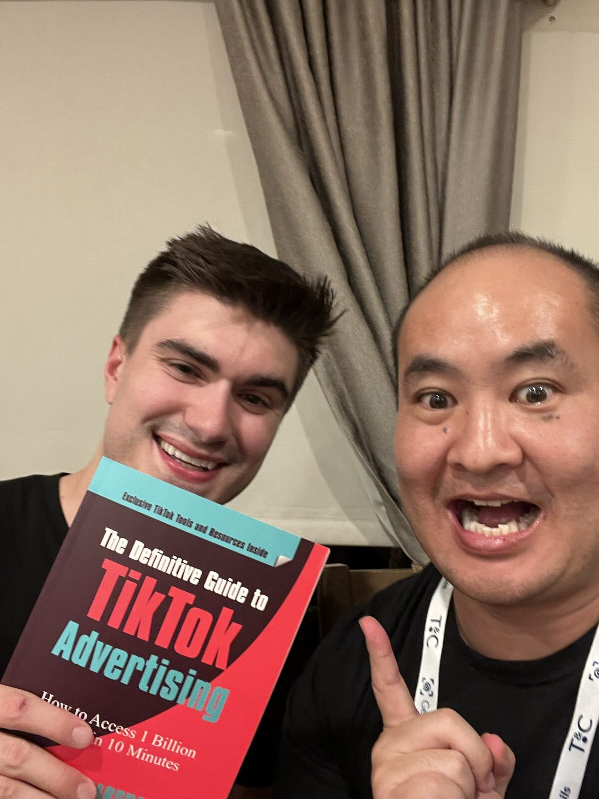 Attendee holding the TikTok book next to Dennis Yu in a Traffic and Conversion Summit lanyard