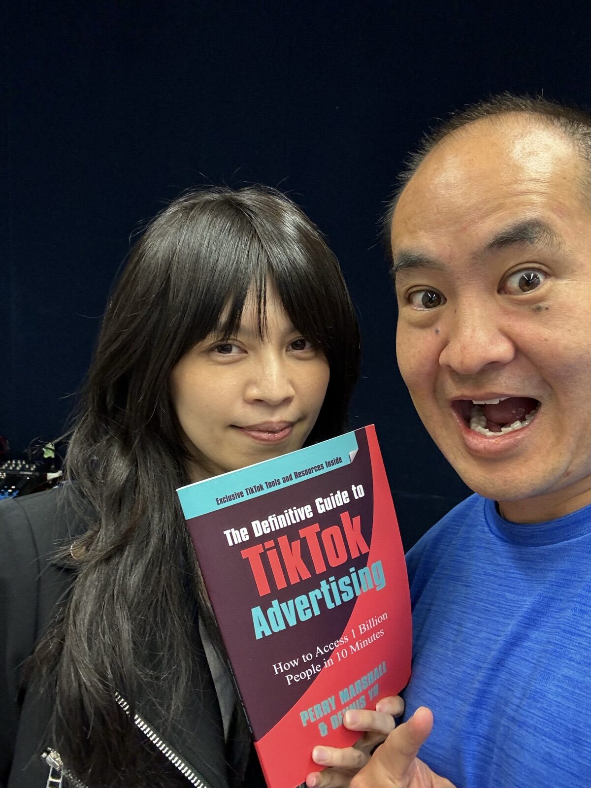 Dennis Yu and a woman holding the TikTok advertising book in a dark conference hall