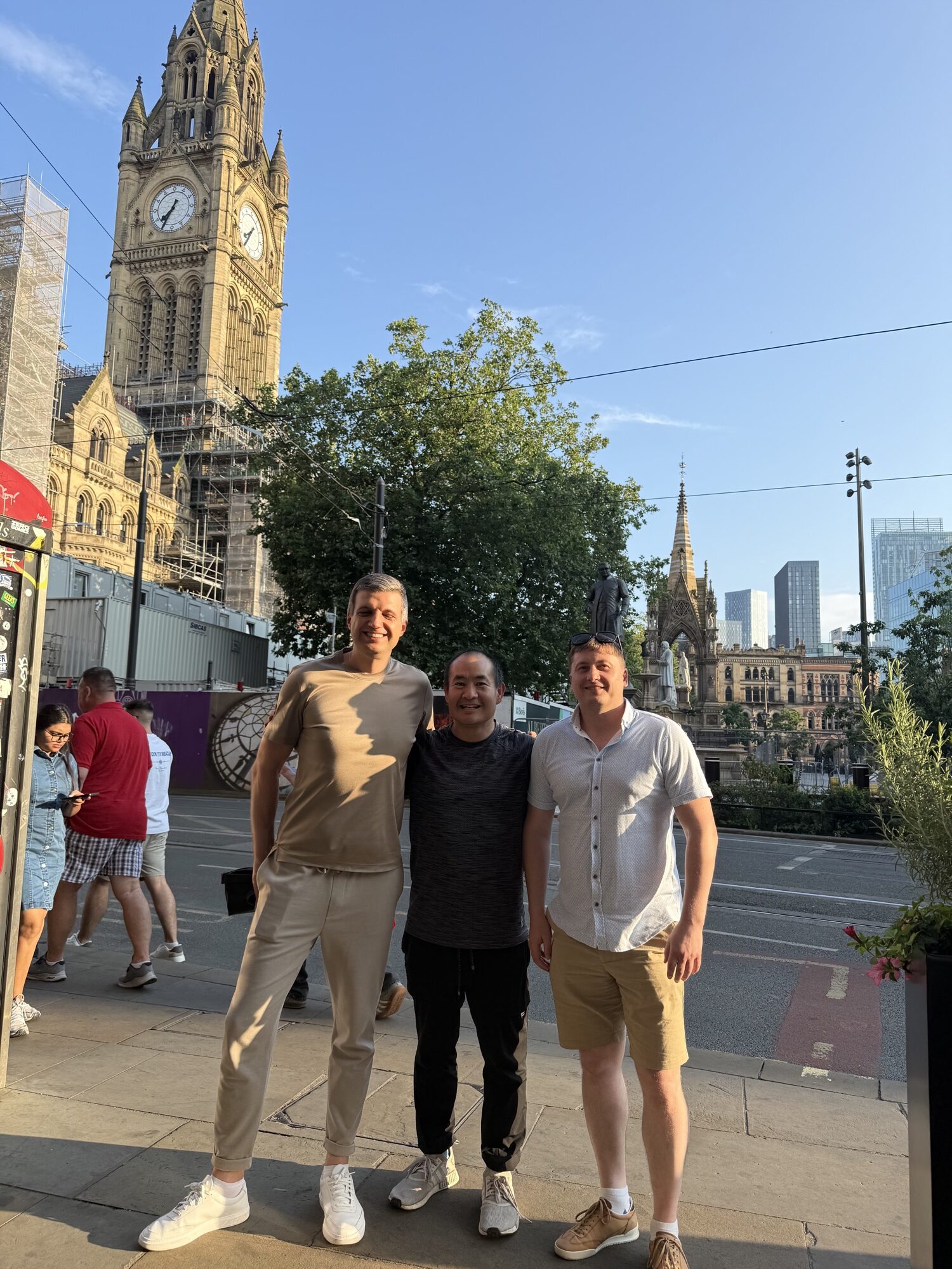 Paul Ryazanov, Dennis Yu, and a colleague in Albert Square, Manchester, July 2026