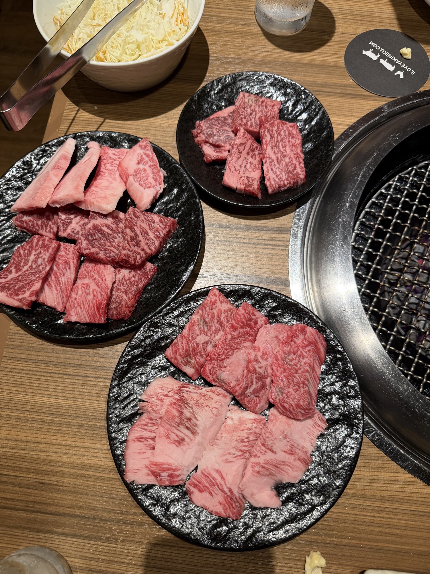 Meatings in Tokyo: Why I Love to EEAT With Good Friends 5 Three plates of raw wagyu next to the grill and a bowl of cabbage salad at Black Hole Shinjuku