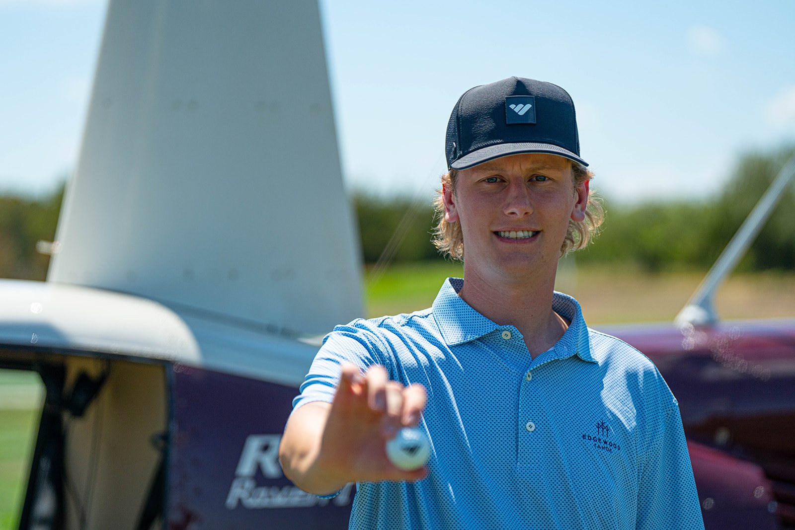 Aden Trano of Whop holding a golf ball in front of the helicopter at the Sphere Rocket Open