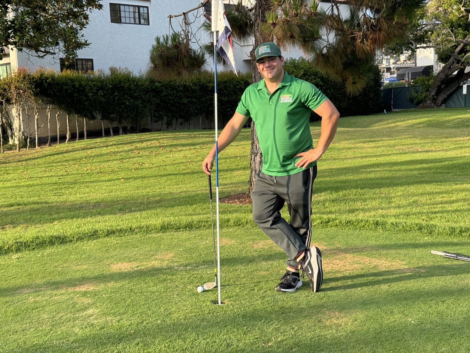 Dennis Yu in a green polo holding the flagstick, July 2024