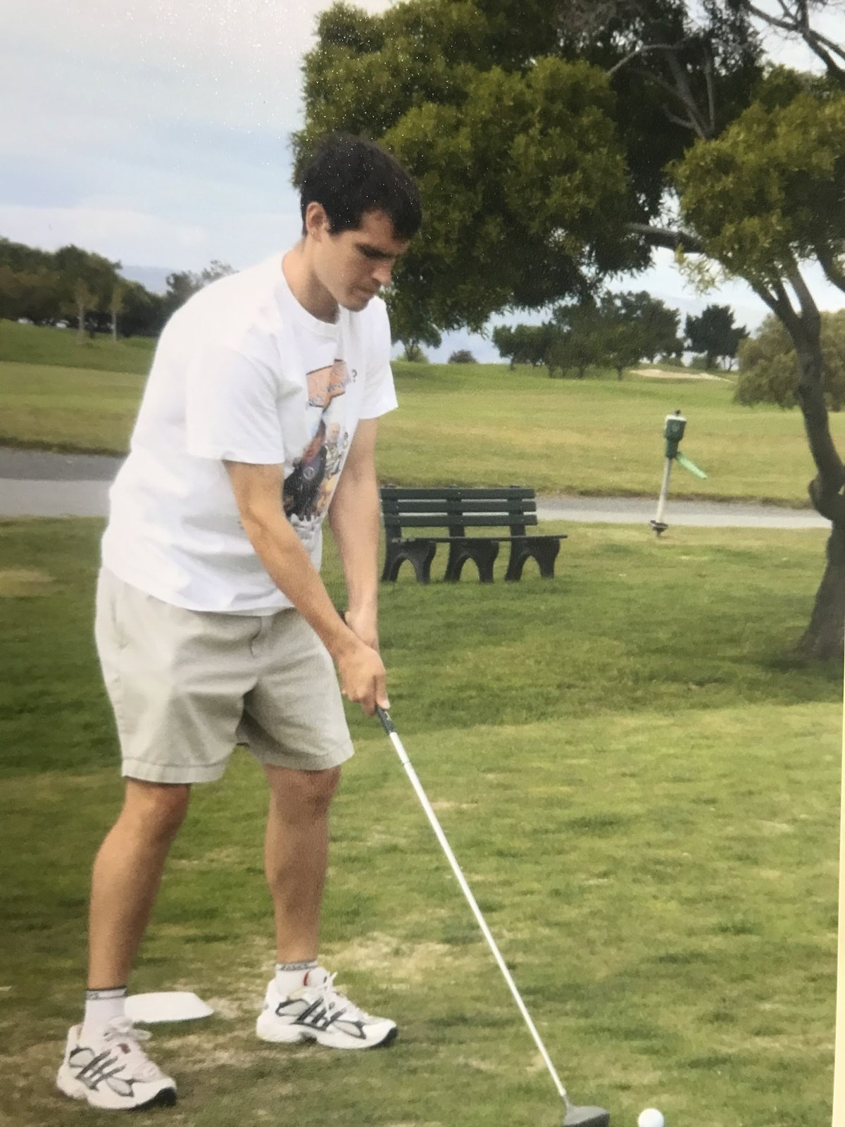 Young Dennis Yu addressing the ball on a fairway, scanned print