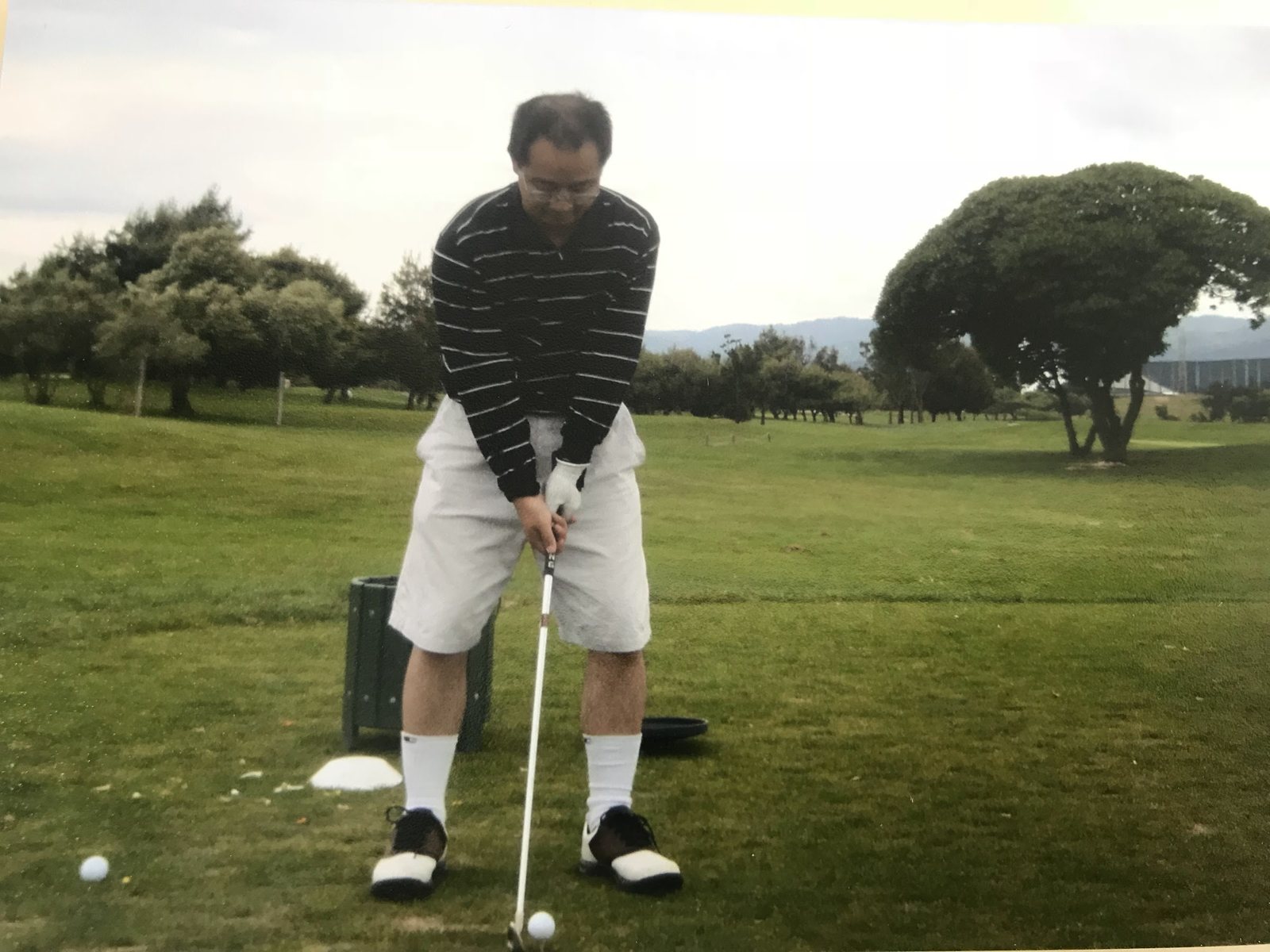 Young Dennis Yu in a striped polo lining up a shot, scanned print