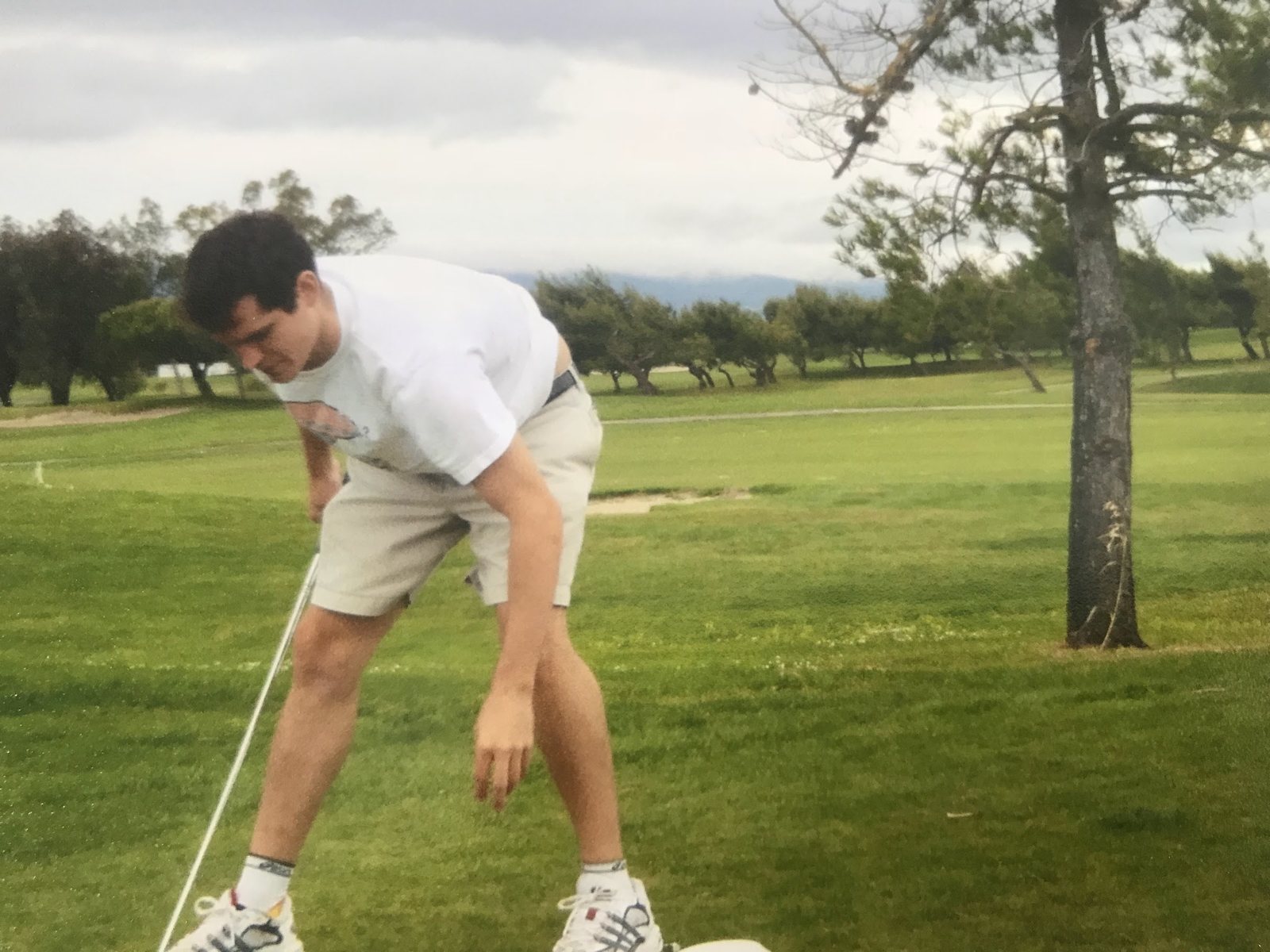 Young Dennis Yu teeing up a ball, scanned print