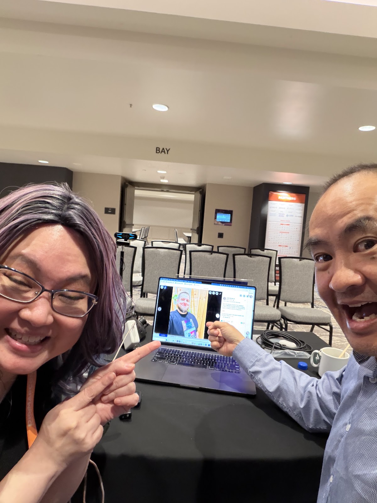 Liana Hosted. I Graded Lamont Brothers in Public. 2 Liana Ling and Dennis Yu pointing at a laptop during DigiMarCon in a conference room labeled Bay