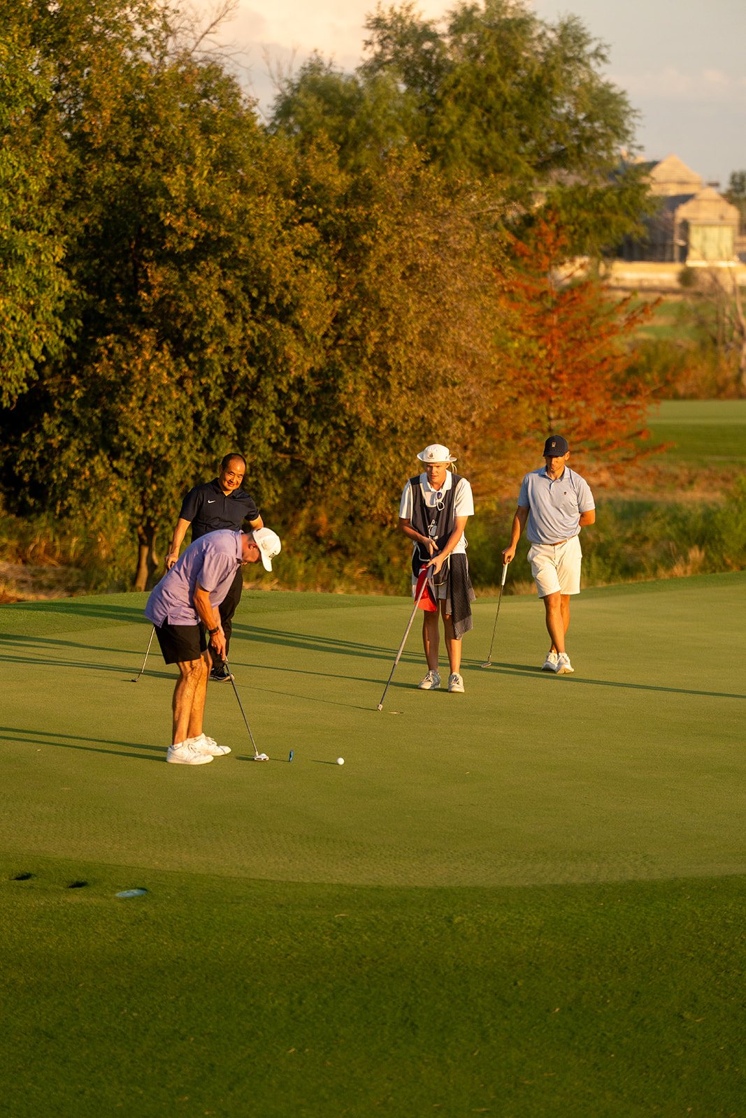 Simon Harries putting while Dennis Yu and Aden Trano watch